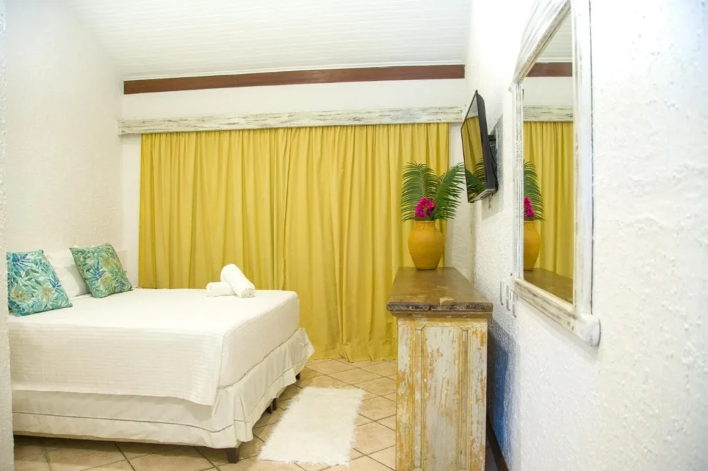Suíte Vista Piscina Superior — Quarto com cama e cortina amarela